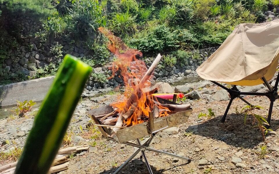 キャンプで冷やしキュウリを食べながら焚き火を楽しむ